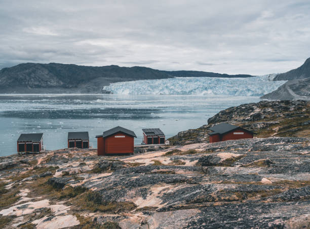 Panoramic image of Camp Eqi at Eqip Sermia Glacier in Greenland. nature landscape with lodge cabins. Midnight sun and pink sky. Tourist destination Eqi glacier in West Greenland AKA Ilulissat and Jakobshavn Glacier. Heavlly affected by Global Warming. Photo taken in Greenland imagen panorámica del campamento eqi en el glaciar eqip sermia en groenlandia. paisaje natural con cabañas de alojamiento. sol de medianoche y cielo rosa. destino turístico glaciar eqi en groenlandia occidental también conocido como ilulissat y glaciar