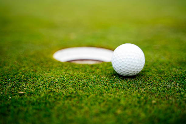 golf ball on the green next to the hole - turf white green horizontal imagens e fotografias de stock