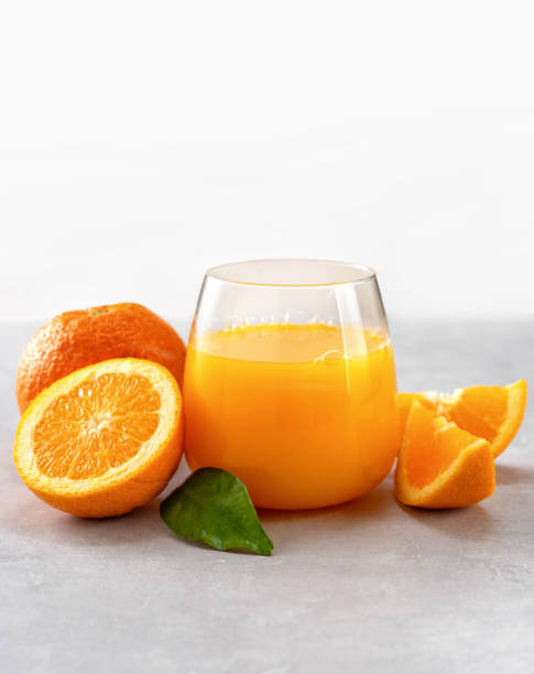 succo d'arancia appena spremuto in un bicchiere - isolated on white orange juice ripe leaf foto e immagini stock