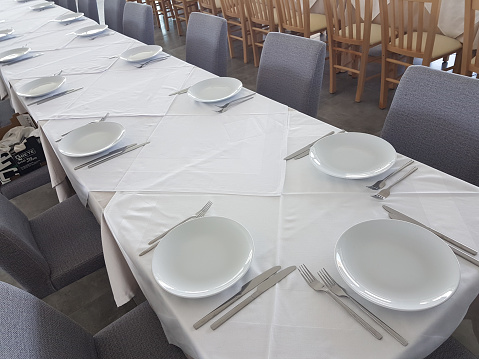 long ready table with  plates forks and spoons empty for background