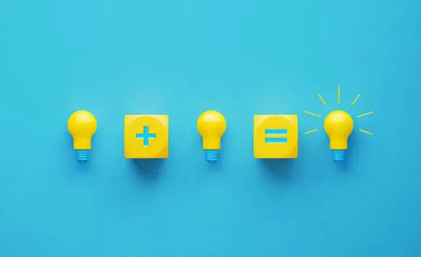 Photo of Light Bulbs and Yellow Cubes with Plus and Equal Signs