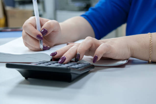 istock Women's hands write in a notebook and count on a calculator 1207166269