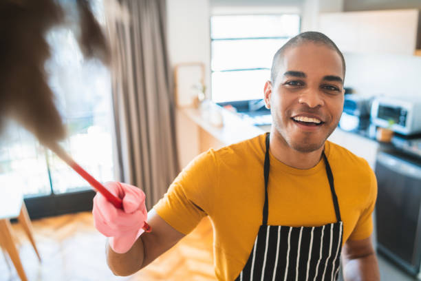 istock Young latin man dusting his new house. 1207167131