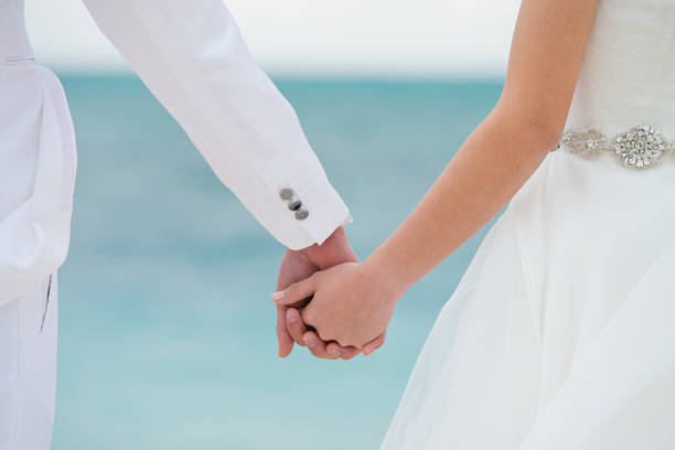 istock Newly weds holding hands on wedding day on beach 1207169339