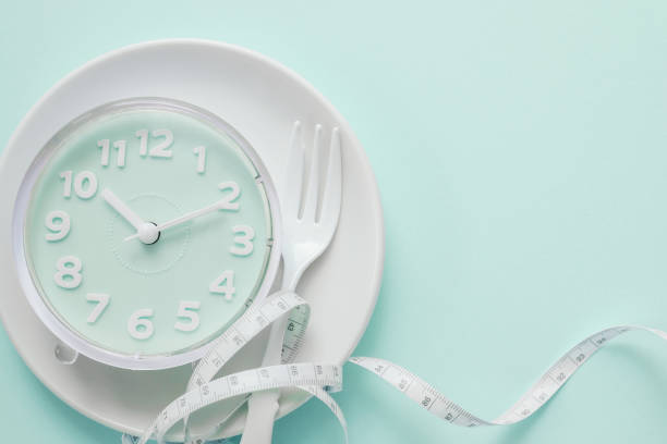 reloj azul en plato blanco, concepto de ayuno intermitente, dieta cetogénica, pérdida de peso, comida salta - ayuno intermitente fotografías e imágenes de stock