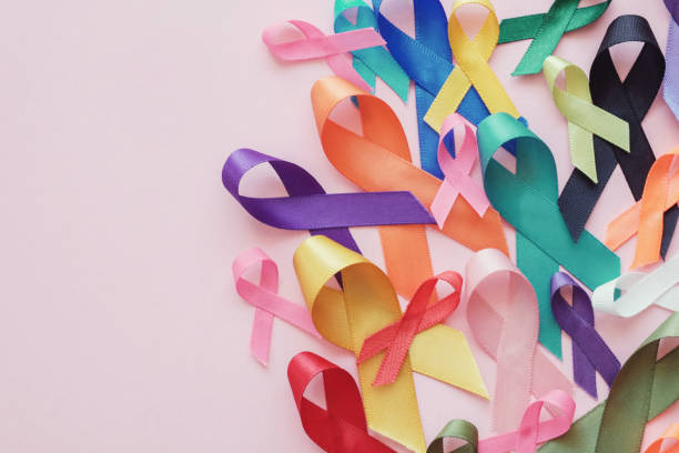 bunte bänder auf rosa hintergrund, krebs bewusstsein, weltkrebstag - cancer stock-fotos und bilder
