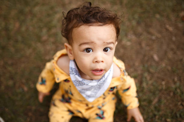 istock Baby boy looking at camera and sitting at ground 1207171196