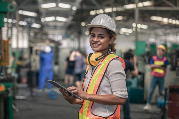 engineer holding digital tablet in hands while working in manufacturing plant - manual worker portrait helmet technology imagens e fotografias de stock