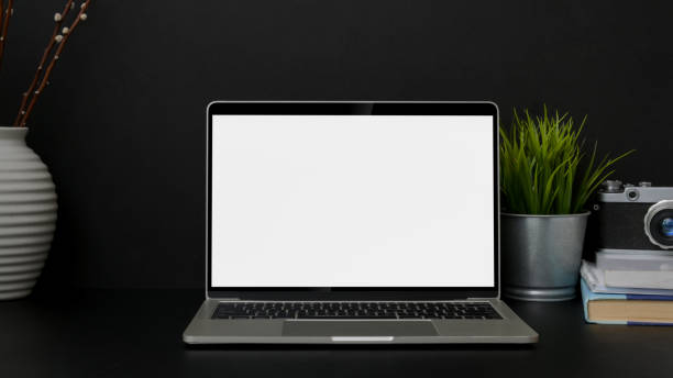 istock Close up view of trendy designer workplace with blank screen laptop on black table 1207185455