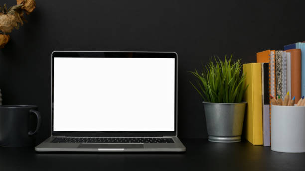 istock Close up view of dark modern workplace with blank screen laptop  with dark wall background 1207185488