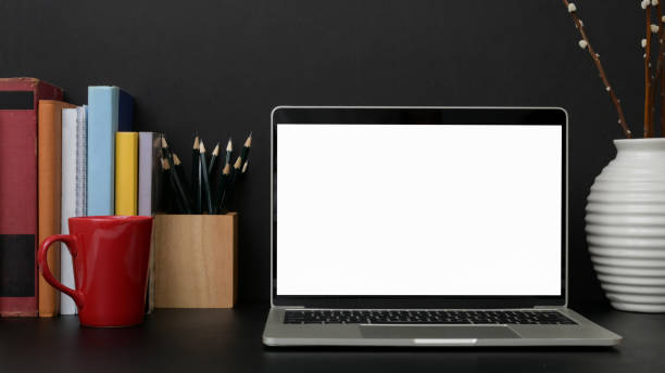 istock Close up view of dark modern workplace with blank screen laptop on black table 1207185565