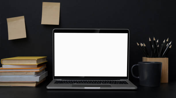 istock Close up view of trendy workplace with blank screen laptop on black table 1207185600