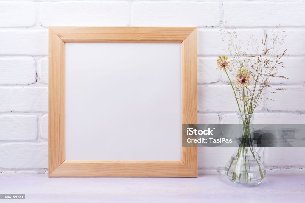 Wooden square frame mockup with grass in the glass jug Wooden square picture frame mockup with wild grass in the glass jug. Empty frame mock up for presentation design. Template framing for modern art. Picture Frame Stock Photo