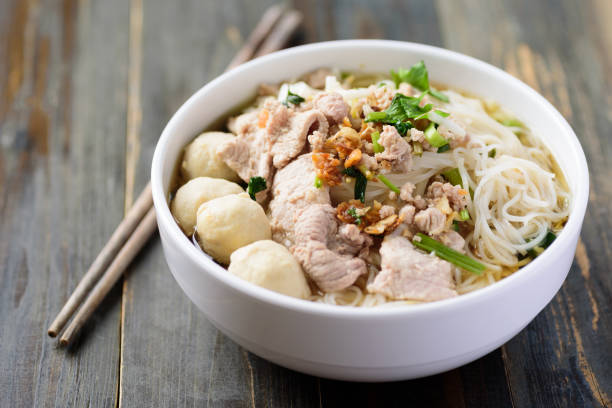 Rice noodles soup with pork and meat ball Rice noodles soup with pork and meat ball in a bowl with chopsticks on wooden table, Thai style noodle soup photos stock pictures, royalty-free photos & images