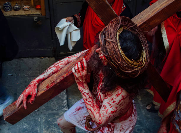 Re0enacting Christ's final hours, covered in blood and under a crown of thorns, a pilgrim carries a cross along the Via Dolorosa in the Old City of Jerusalem on Good Friday.