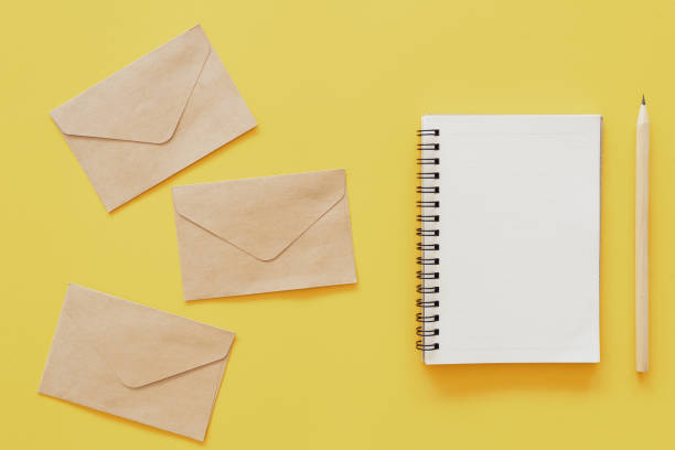 istock Brown paper envelope and notebook with pencil on yellow pastel abstract background. 1207199236