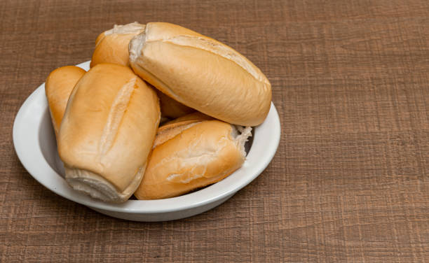 uma tigela pequena com pães de trigo recém-cozidos colocados em uma mesa de madeira - french loaf - fotografias e filmes do acervo