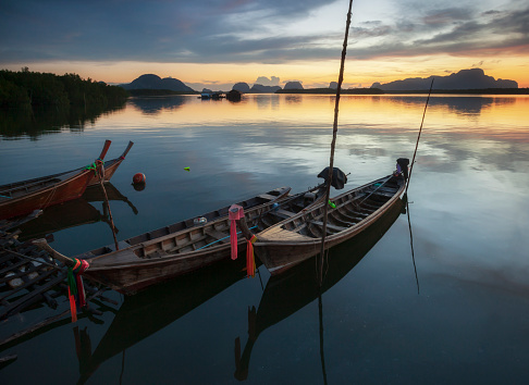 Beautiful sunset of fishing village in Phang Nga Bay with longtail wooden fishing  boat ,Thailand
