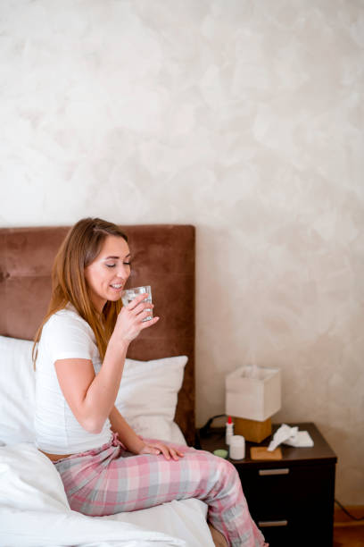 istock Young woman taking pills in bedroom 1207201033