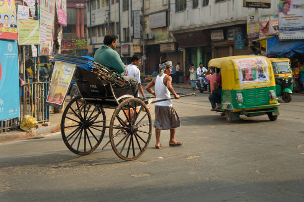 Kolkata, India - March 13, 2019: Man rickshaw puller is pulling his hand rickshaw with passenger on the street