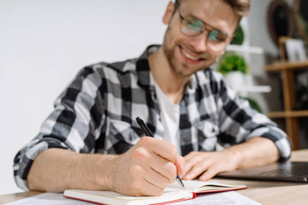istock Young adult freelancer writing his notes in organizer 1207203980