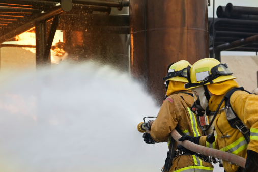 Focus is on the firefighter in the front holding the nozzle.