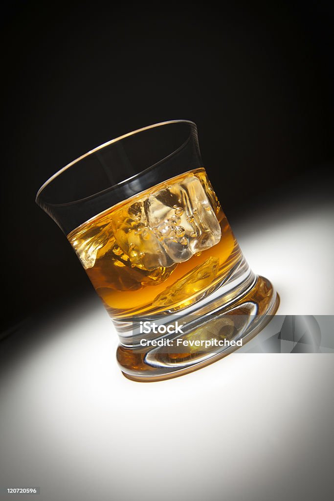 Vaso de whisky y el hielo bajo luz puntual. - Foto de stock de Alcoholismo libre de derechos