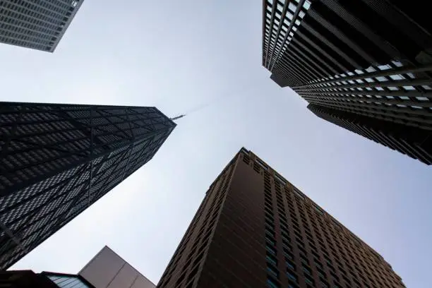 Photo of Bottom view of modern office buildings in financial district at sunset, real estate and success concept, USA