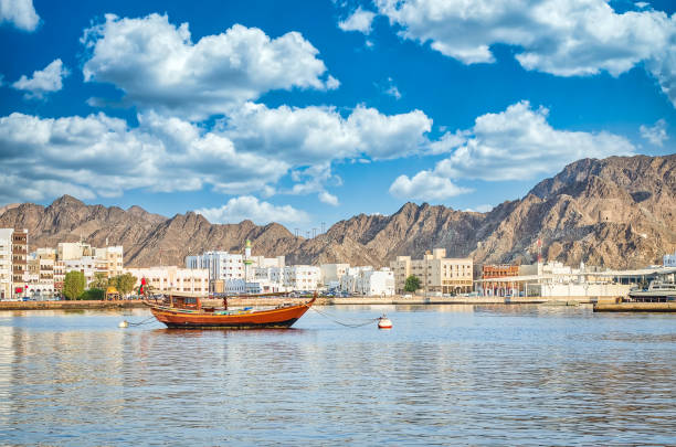 Old Sailboat at the Muttrah Port Old Sailboat anchored at Muttrah Corniche. The the old city and mountains in the background. From Muscat, Oman. dhow photos stock pictures, royalty-free photos & images