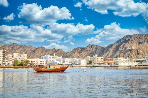 Old Sailboat anchored at Muttrah Corniche. The the old city and mountains in the background. From Muscat, Oman.