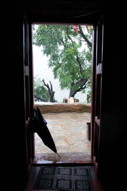 istock Closed umbrella in front of village mud house during rainfall 1207211516