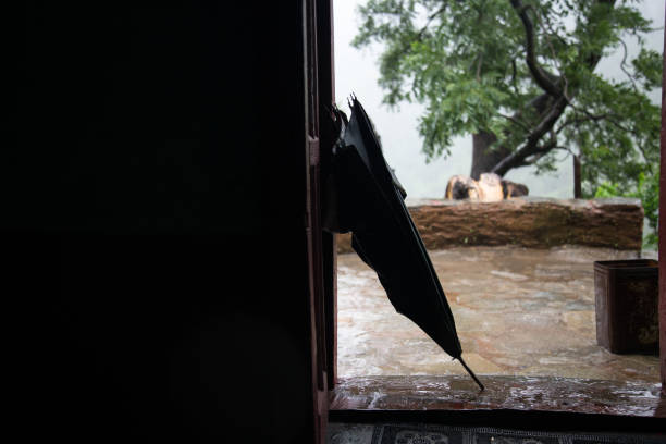 Closed umbrella in front of village mud house during rainfall