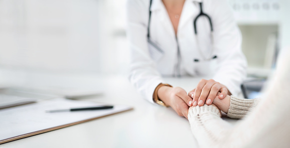 Closeup shot of an unrecognizable female doctor holding a patient's hand in comfort during a consultation inside her office