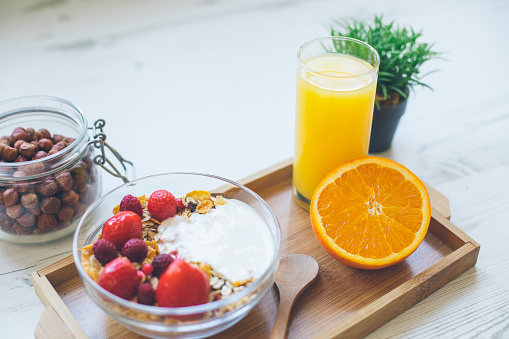 healthy food granola breakfast with fresh red berries, orange, hazelnuts and orange juice