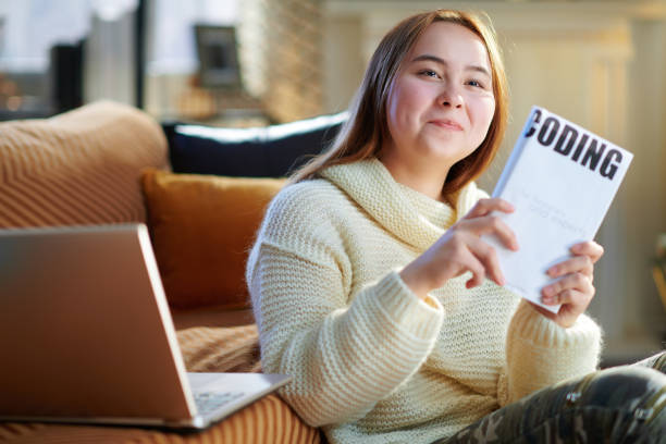 istock happy young woman with laptop showing educational coding book 1207219686