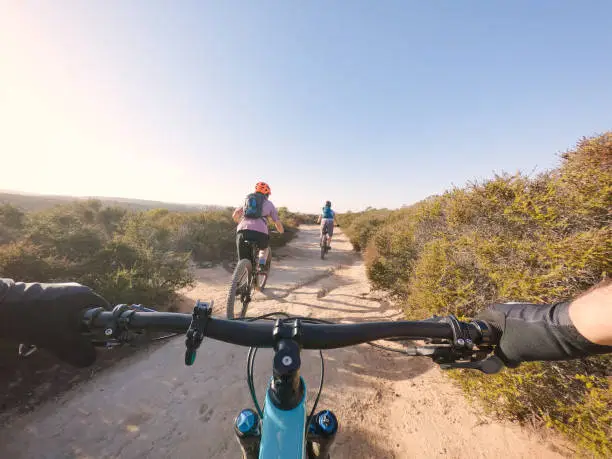 Women and man exploring on single track trail through hills of California, USA