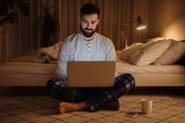istock Young man using his laptop while sitting on the floor at home 1207222270
