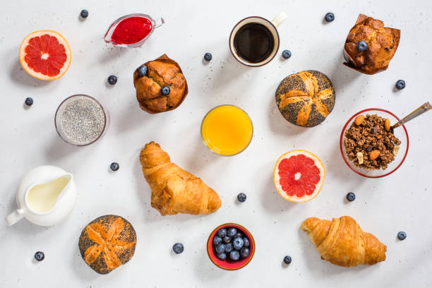 Modern continental breakfast, top view Modern continental breakfast, top view. Coffee, orange juice, milk, poppy seed buns, blueberry muffins,  croissants, granola, chia pudding, blueberries. continental breakfast stock pictures, royalty-free photos & images