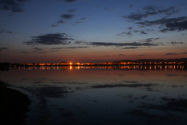 View up the shoreline of Ventura coasts with city lights reflecting into the ocean water under bright stars in the sky.