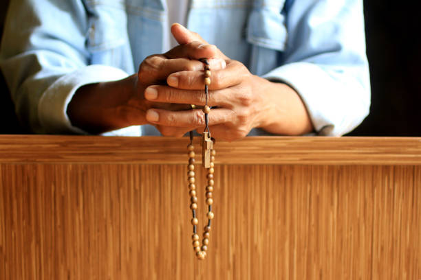 Senior man kneel praying rosary.