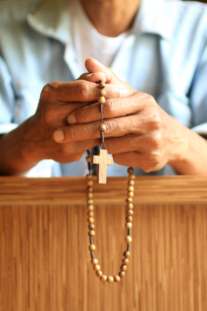 istock Senior man kneel, hands holding rosary in prayer pose. 1207231192