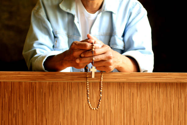 istock Senior man kneel praying rosary. 1207231208