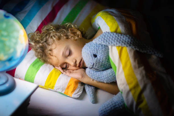 Child sleeping at night. Kids sleep. Child sleeping at night. Kids sleep. Little boy relaxing in bed with rainbow stripe blanket holding soft bunny toy. baby sleeping bedding bed stock pictures, royalty-free photos & images