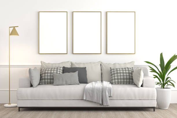 istock Interior design setup, modern elegant living-room consisting of white couch with various pillows and textiles, lamp and plant on a pot on white wall with framed blanck canvas for mock up 3d render. 1207239901