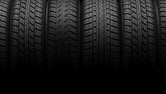 A set of car wheels or tires lie in a row in the shadow on a black background. Mock up for advertising car service or auto maintenance. Copy space. 3D rendering.