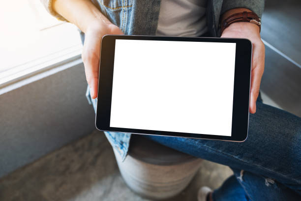 istock a woman holding and showing black tablet pc with blank white screen in cafe 1207247337