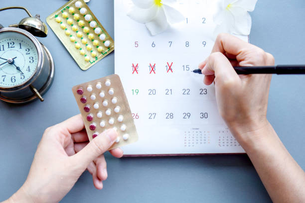 frau hand hält antibabypillen und markieren sie das datum im kalender - alternate medicines stock-fotos und bilder