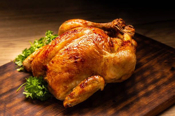 Roasted whole chicken on wooden cutting board.