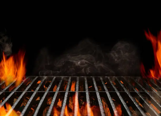 Photo of Hot empty portable barbecue BBQ grill with flaming fire and ember charcoal on black background. Waiting for the placement of your food. Close up