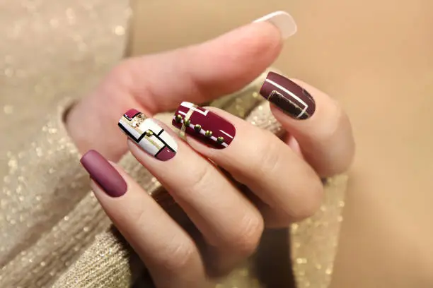 Burgundy and white design on long nails with Golden lines.Fashionable matte glossy nail art.